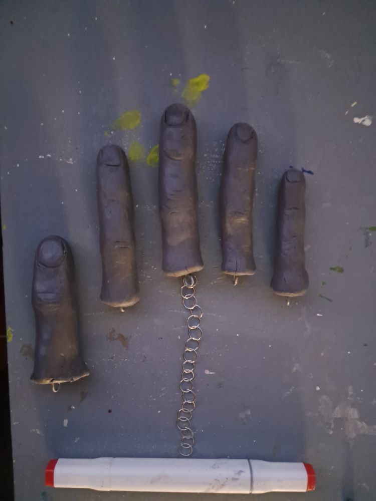 5 dedos hechos de arcilla unidos a una cadenita