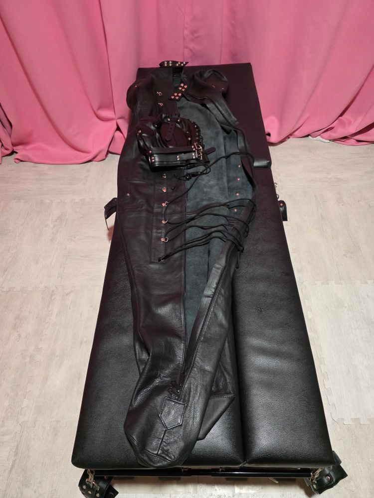 A leather body bag and hood on a table.