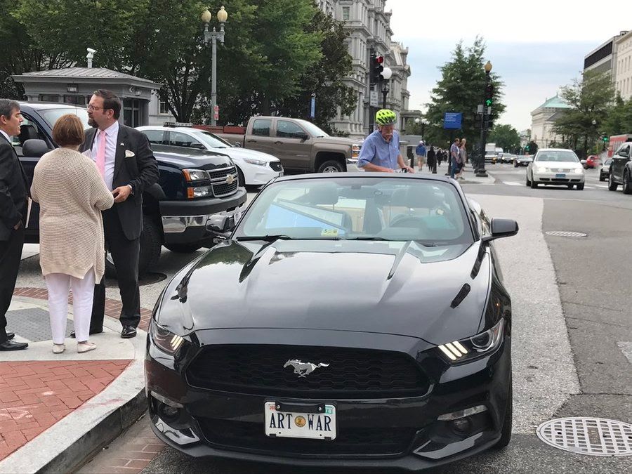Seb Gorka outside on a street in Arlington next to a black mustang with the license plate 