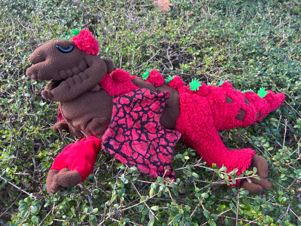 A brown and red plush dragon with a skeleton head