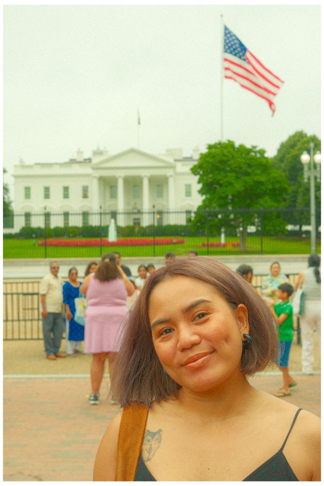 Me smiling near the White House in Washington, D.C., with the U.S. flag flying above the building and tourists gathered in the background.