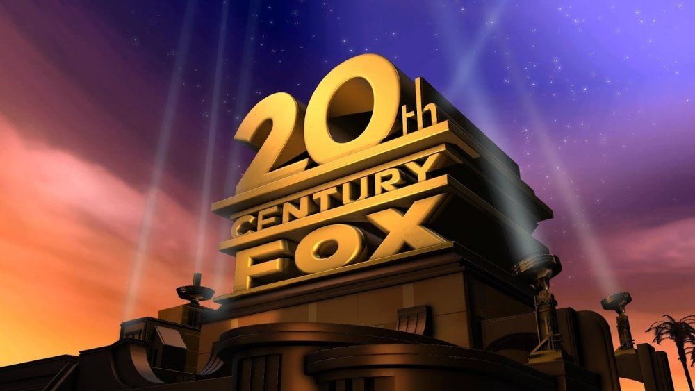 A still from the 20th Century FOX movie company introduction. It shows the 20th Century FOX logo against a multicolored sky, perched atop idealized 1950s architecture and surrounded by spotlights.