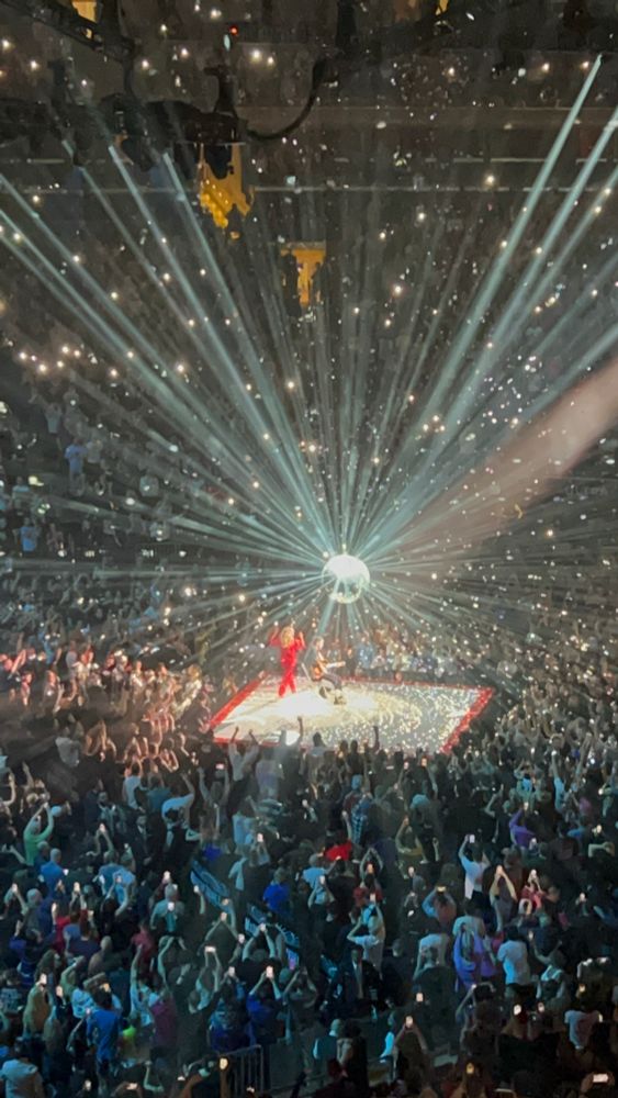 Kylie Minogue, wearing a red outfit, on a smaller stage with a disco ball beaming all around.