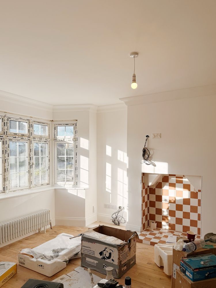 Living room. Builders tools on the floor. Chequered tiles ln wall.