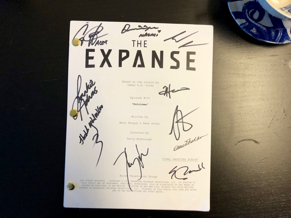 A copy of the script to The Expanse Season 1, Episode 1. It’s held together with brads and signed in Sharpie marker by the main cast and crew. Some of the main cast members have written their characters’ names beside their signatures, perhaps because it was early enough in the show’s run that they didn’t expect their own names to be recognized. 