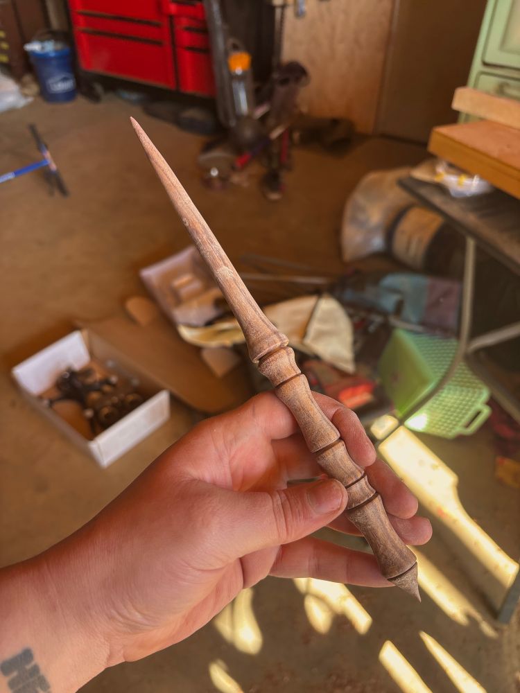 Unfinished/raw wood support spindle being held in hand with finger bone inspired designs