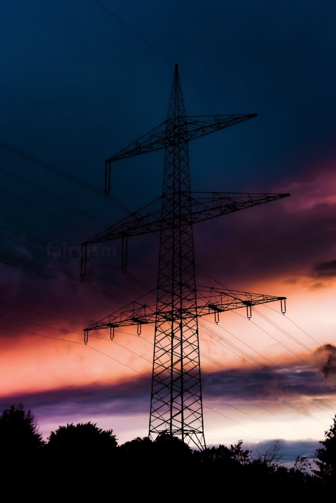 Vertical sunset capture of a big pylon against the cloudy and colourful sunset sky. In the sky are many clouds, and the colours range from teal, purple, orange to red.