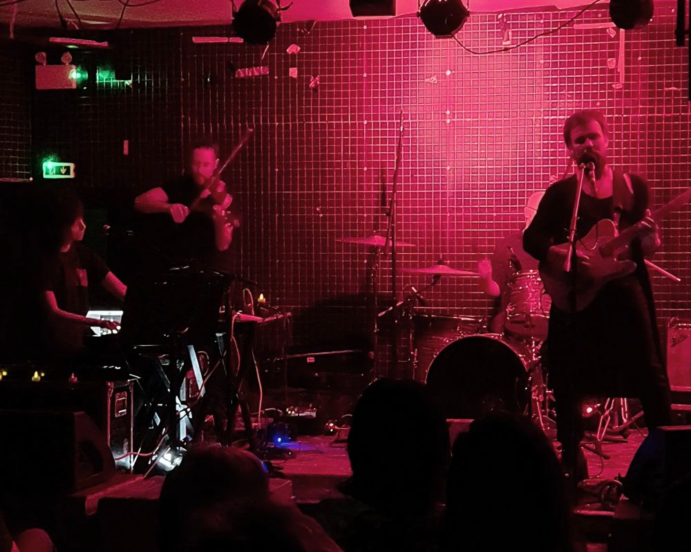 Alora Crucible playing the music of Toby Driver at a UK exclusive Chaos Theory event in New River Studios.

Members from left to right:
Ana Cristina Pérez Ochoa on piano/synth
Timba Harris on violin
Sam Gutterman on drums
Toby Driver on guitar and vocals