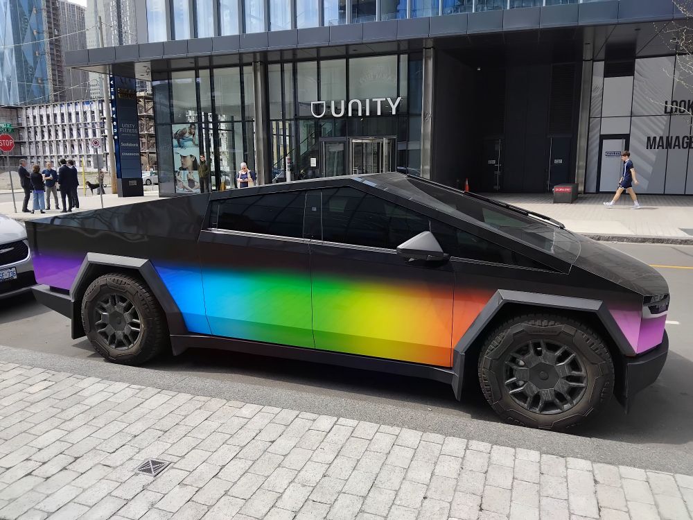Tesla Cybertruck in rainbow colors in front of a gymn