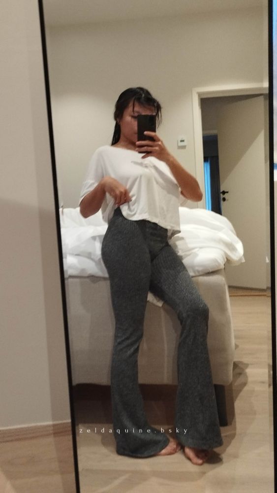 Asian Findom God Zeldaquine in front of the mirror wearing a thin loose shirt that subtly emphasizes her perky breasts, and tight stretchy flare pants that firmly grasp her butt, legs, her bulging front, and her toes just peaking at the wide bottoms. An ultimate trigger for foot and ass lovers.