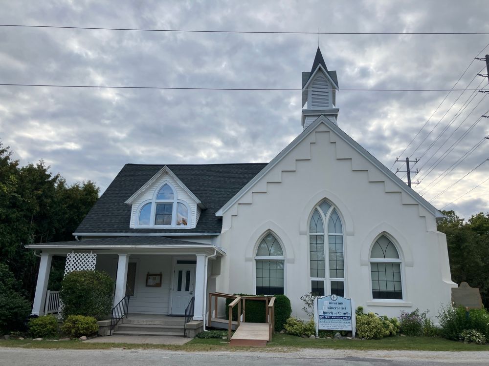 A picture of a small white church with a covered porch. 