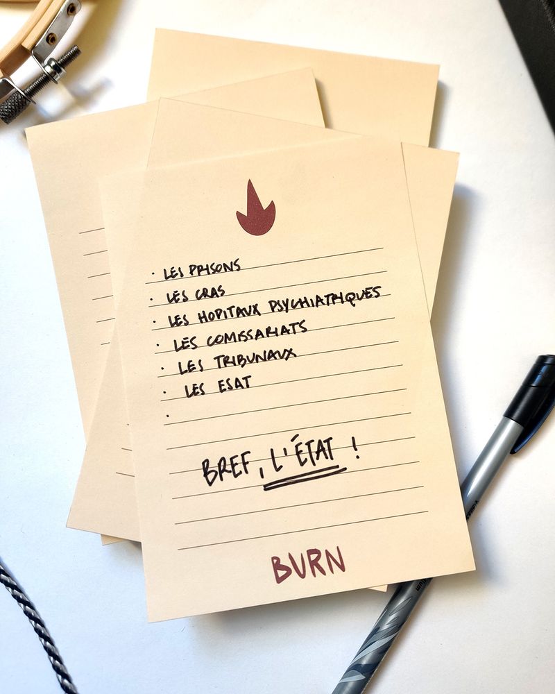 Photo d’une pile de bloc notes. Sur la première page du bloc notes du dessus, il est inscrit : les prisons, les CRAs, les hôpitaux psychiatriques, les commissariats, les tribunaux, les ESATs. Bref, l’Etat.