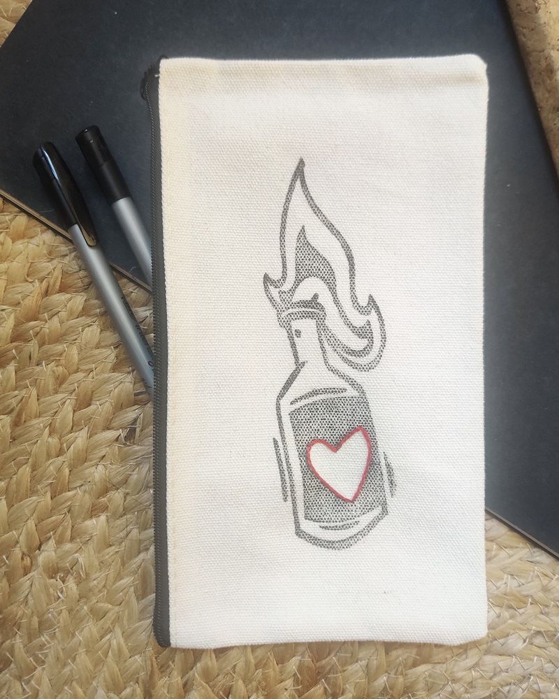Photo d’une pochette en coton sur laquelle a été imprimée via la gravure un mololove. Le mololove est un cocktail molotov avec un coeur dessus pour une explosion d’amour. Le coeur a également été brodé au fil rouge par dessus la gravure.