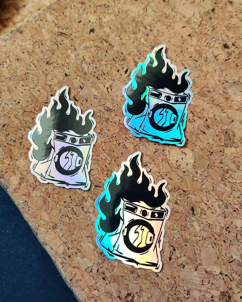 Trois stickers de machine à laver posés sur un carnet en liège.