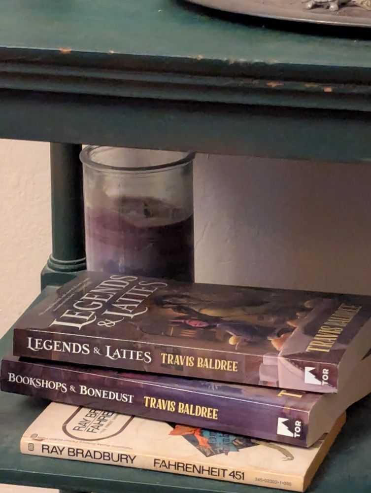 Two books, Legends & Lattes, and Bookshops & Bonedust, both covers illustrated by OP.
Fahrenheit 451 is underneath them but that's not relevant