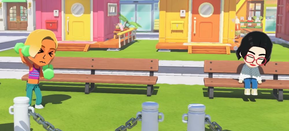 screenshot 1 from tomodachi life 2 trailer: background is a colorful town in the background, and in the foreground has two brown public benches on top of a patch of green grass. there are also some white poles with chains closer to the camera.

person on the far left is femme, has a orange-leaning tan and has blonde hair. they’re wearing a cropped tanktop with hot pink trim, and light blue and purple stripes. they’re also wearing teal drawstring sweatpants with white shoes. they’re working out next to a bench with neon green weights with a strained face.

the other person on the far right is also femme, is much paler and has short black hair. they have thick black eyebrows, red glasses, and red lips. they are also wearing a white long sleeve button-up top with tiny black polka dots, some blue jeans and beige lace-up shoes, reminiscent of Converse. they are currently asleep on the second bench, in a sitting position with their head drooping downward.
