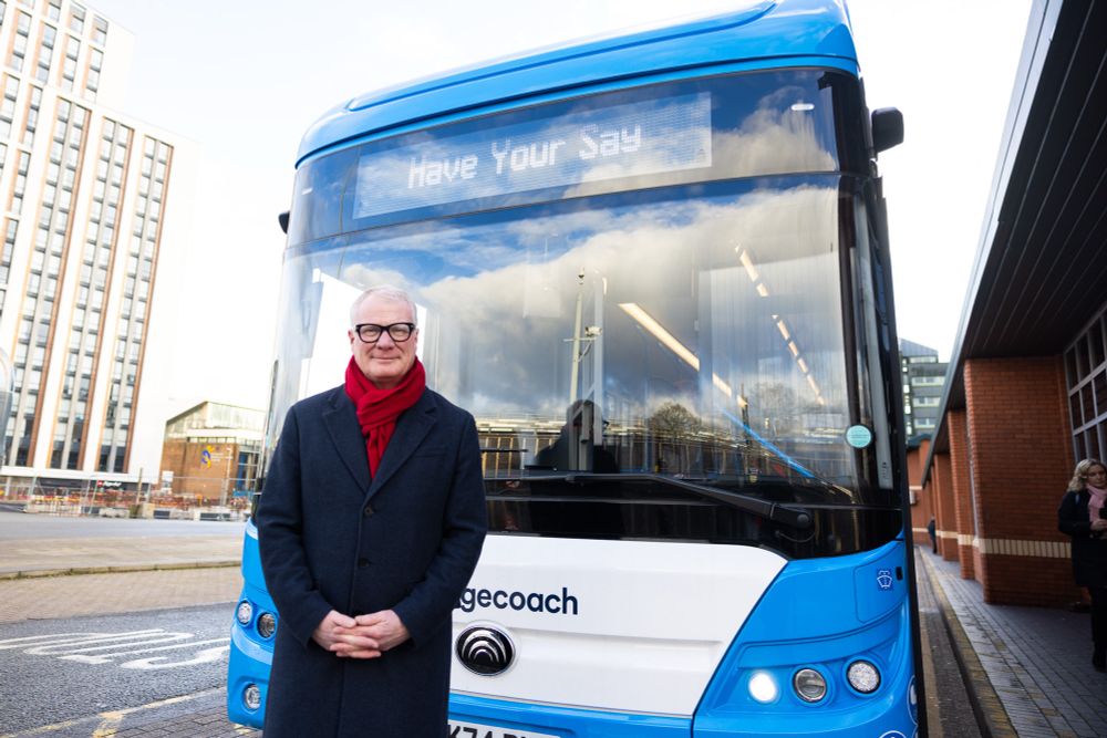 A man (Mayor Richard Parker) standing in front of a bus. The sign on the bus display reads 'Have your say'