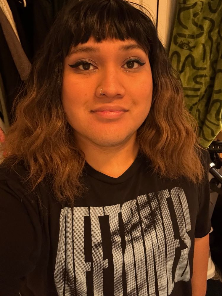 Selfie of Ray, wearing a medium bob wig with bangs and blonde tips. She is also wearing a Deftones band tshirt. 