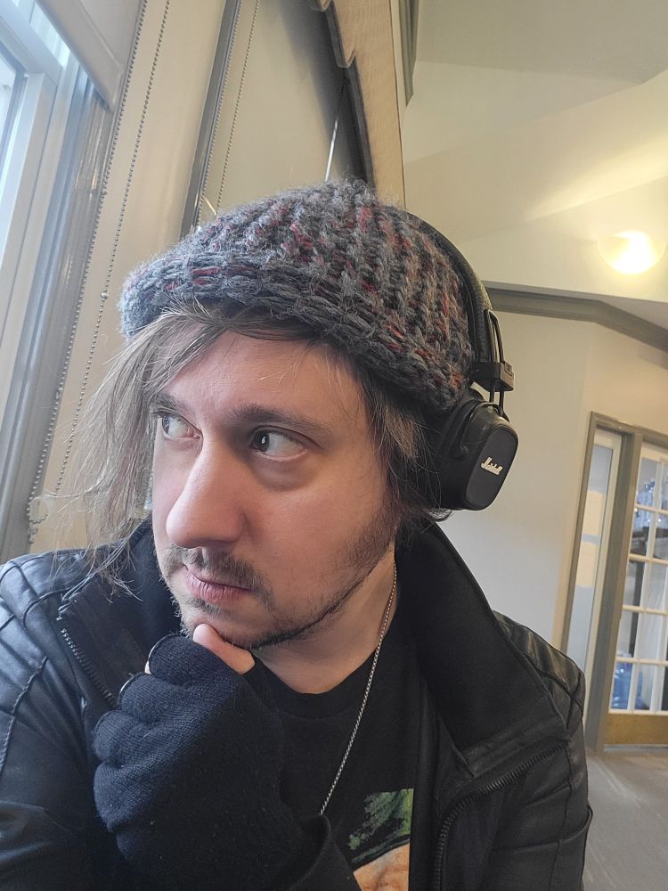 Nick Taxidermy, a goth in his early forties, looking out of a window. 