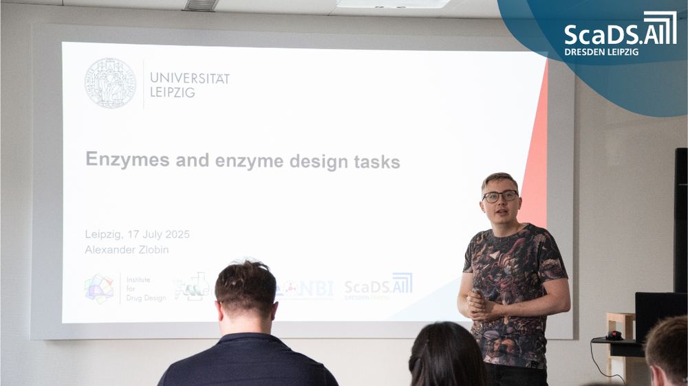 Alexander Zlobin standing left to a podium, presenting a slide titled “Enzymes and Enzyme Design Tasks” dated “Leipzig, 17 July 2025,” with Institute for Drug Design, NBI, and ScaDS.AI logos visible, as a seated audience listens.