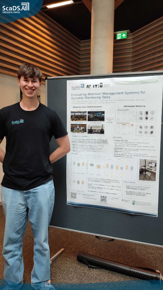 Smiling young man standing next to a poster titled "Evaluating Attention Management Systems for Dynamic Monitoring Tasks" at a conference.