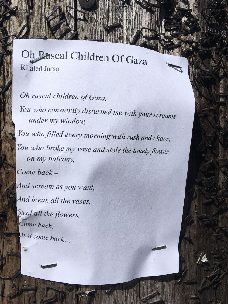 Poem "Oh Rascal Children Of Gaza" by Hkaled Juma, posted publicly in a Toronto neighborhood a year ago. There were still a lot of buildings standing then. Text:
Oh, rascal children of Gaza,
You who constantly distrubed me with your screams under my window,
You who filled every morning with rush and chaos,
You who broke my vase and stole the lonely flower on my balcony,
Come back - - 
And scream as you want,
And break all the vases,
Steal all the flowers,
Come back,
Just come back...
You who 
