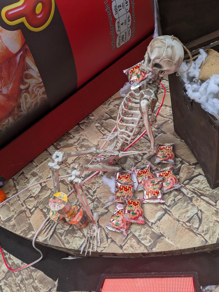 A picture of a skeleton eating several packets of noodles. He died doing what he loved.