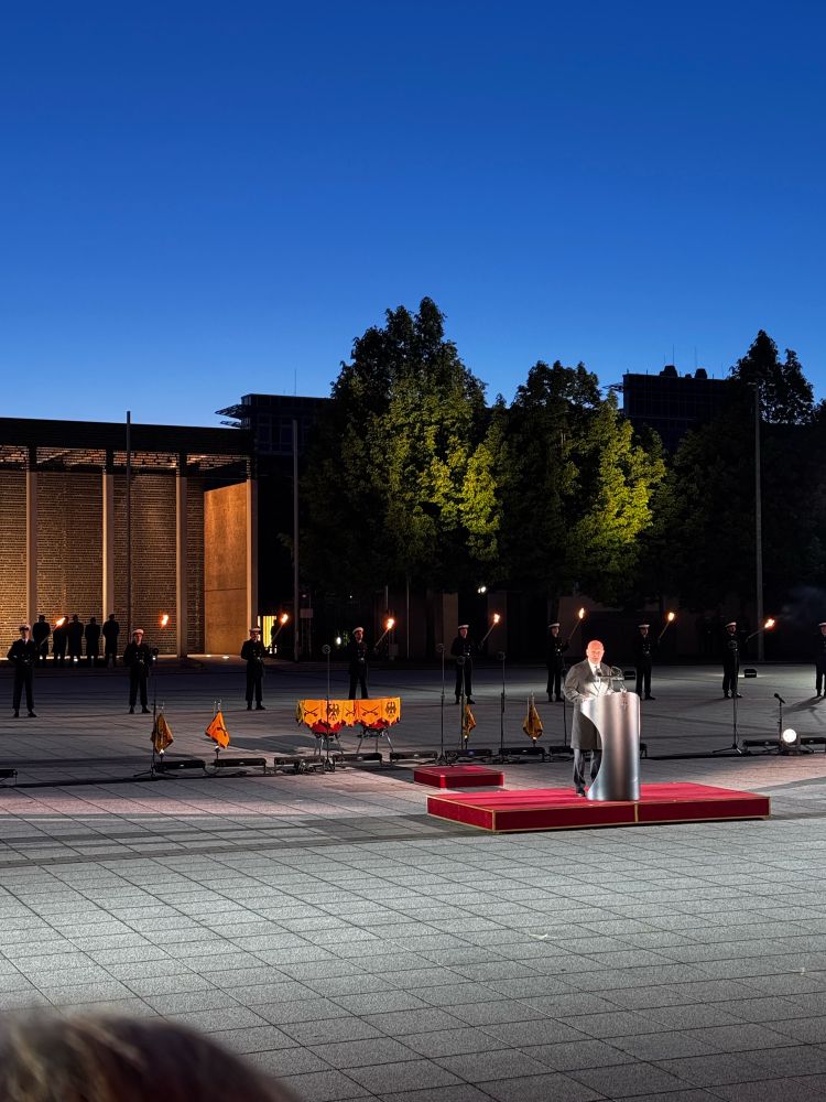 Olaf Scholz auf dem Platz am Bendlerblock, vor einem Pult. Im Hintergrund das Wachbataillon der Bundeswehr.