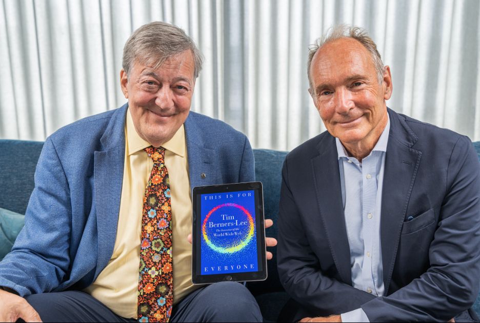 Sir Tim Berners-Lee sat next to Stephen Fry holding the cover of Tim's new book THIS IS FOR EVERYONE