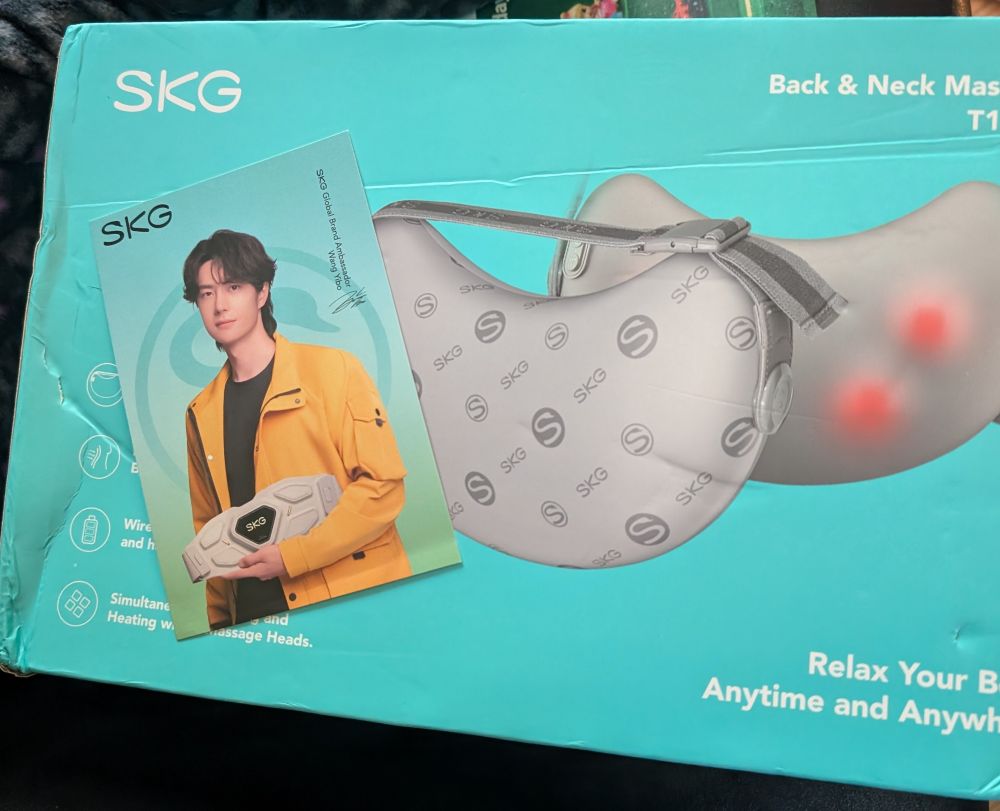 A box containing an skg back and neck massager with a Yibo collector's card lying on top of it.