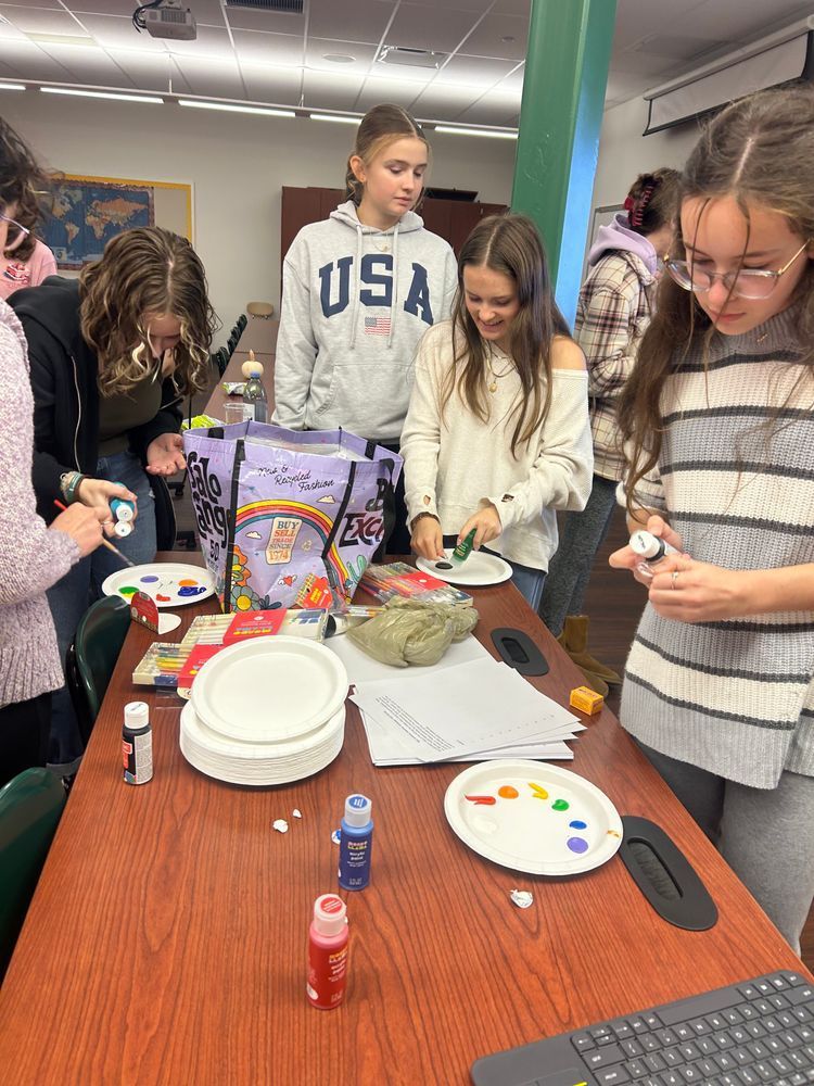 five students add paint to their pallettes