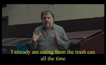 Zizek in front of a dumpster, suspiciously wearing an unstaned shirt, saying he eats trash, but nobody is sure if this is a metaphor. Philosophy!
