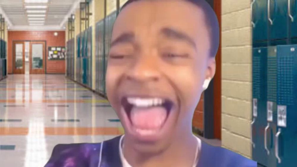 a boy is making a funny face in a hallway with lockers in the background .