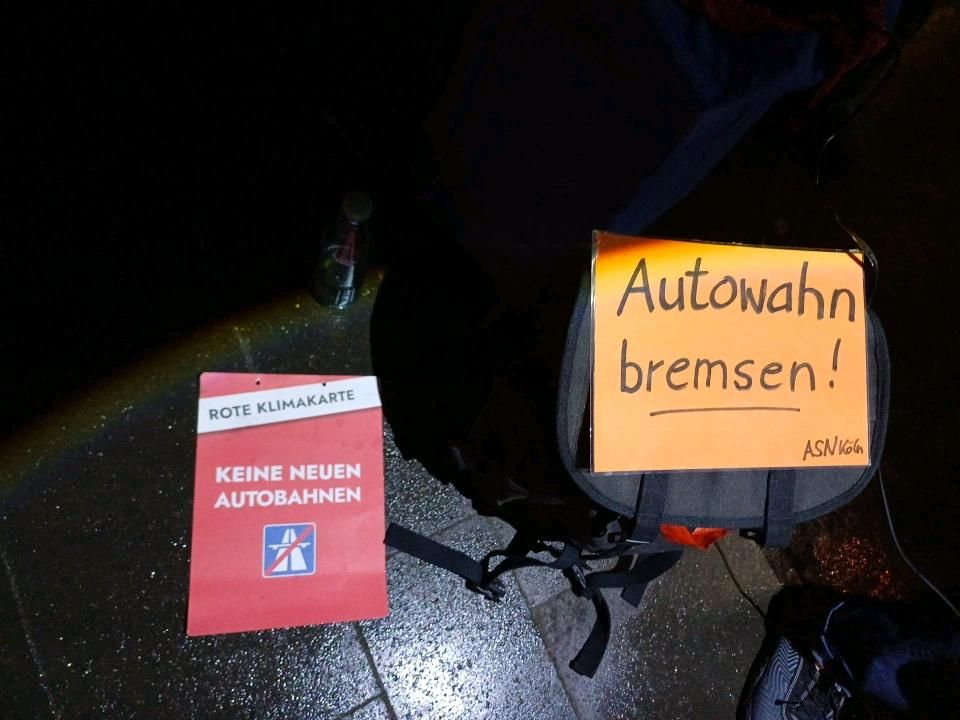 am Boden liegende Plakate: "Rote Klimakarte - Keine neuen Autobahnen" und "Autowahn bremsen (ASN Köln)"