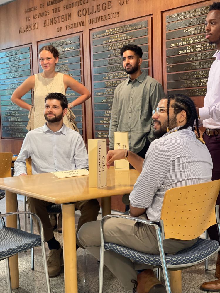 New Medical Scientist Training Program students standing and seated at table at Forchheimer Medical Science Building. 