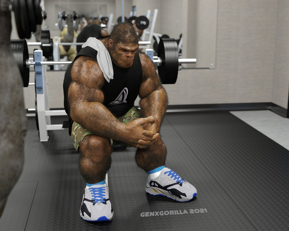 A muscular male gorilla-kin wearing a black tank top with white logo on the chest, camo print cargo pants, running shoes, with a white towel draped over his right shoulder. He is sitting on the edge of a flat bench press, leaning forward, his arms resting on his legs. His hands are interlocked with each other as he gazes absentmindedly at the ground taking a breather.
Behind him is a mirror reflecting a blurry image of the rest of the gym with a couple more gym-goers working out.