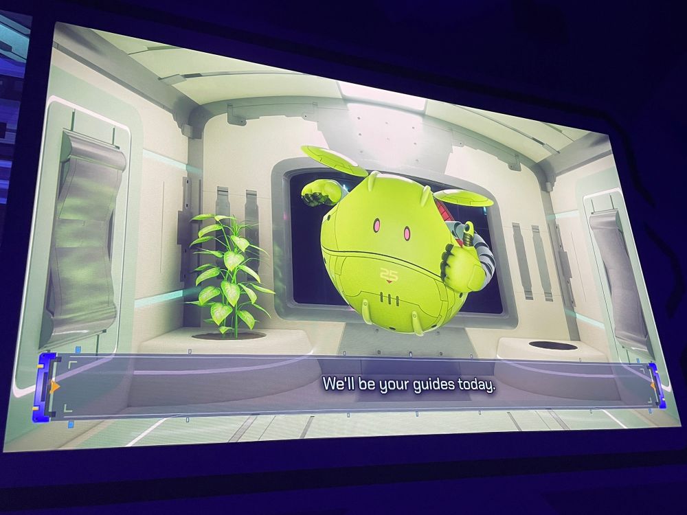 ガンダムパビリオンの映像でサムズアップ しているハロの写真。下に『We'll be your guides today.』の字幕