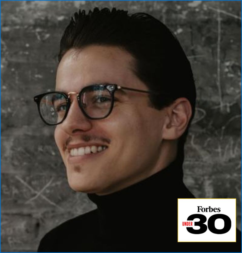 Portrait of a smiling individual wearing glasses and a black turtleneck, with a Forbes Under 30 badge at the bottom.