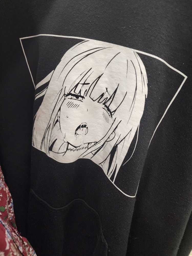 A black fleece hoodie with a white ahego face panel printed on it 