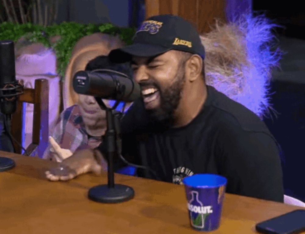 a man wearing a lakers hat is laughing while sitting at a table