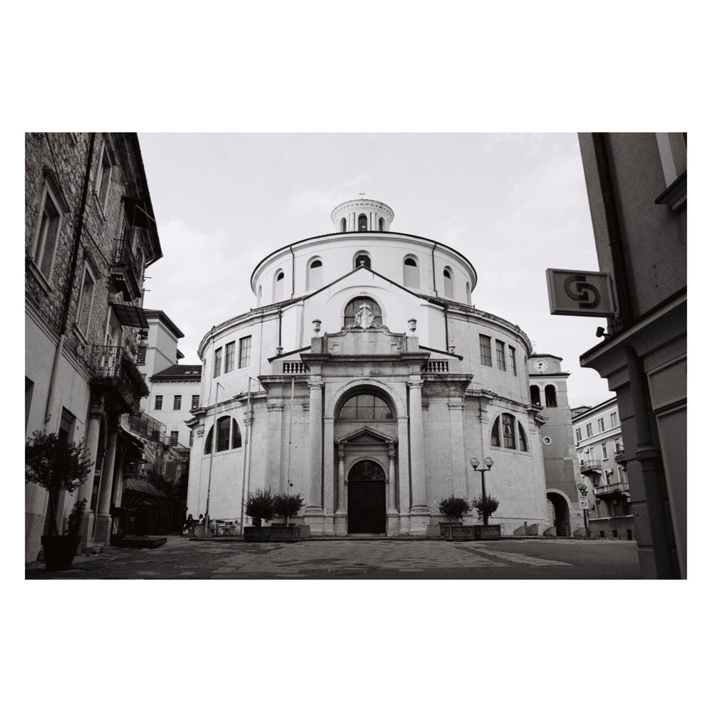 Black and white photo of the Katedrala sv. Vida (St. Vitus Cathedral) in Rijeka, Croatia, a large, circular, domed building with a classical facade, situated on a paved square.