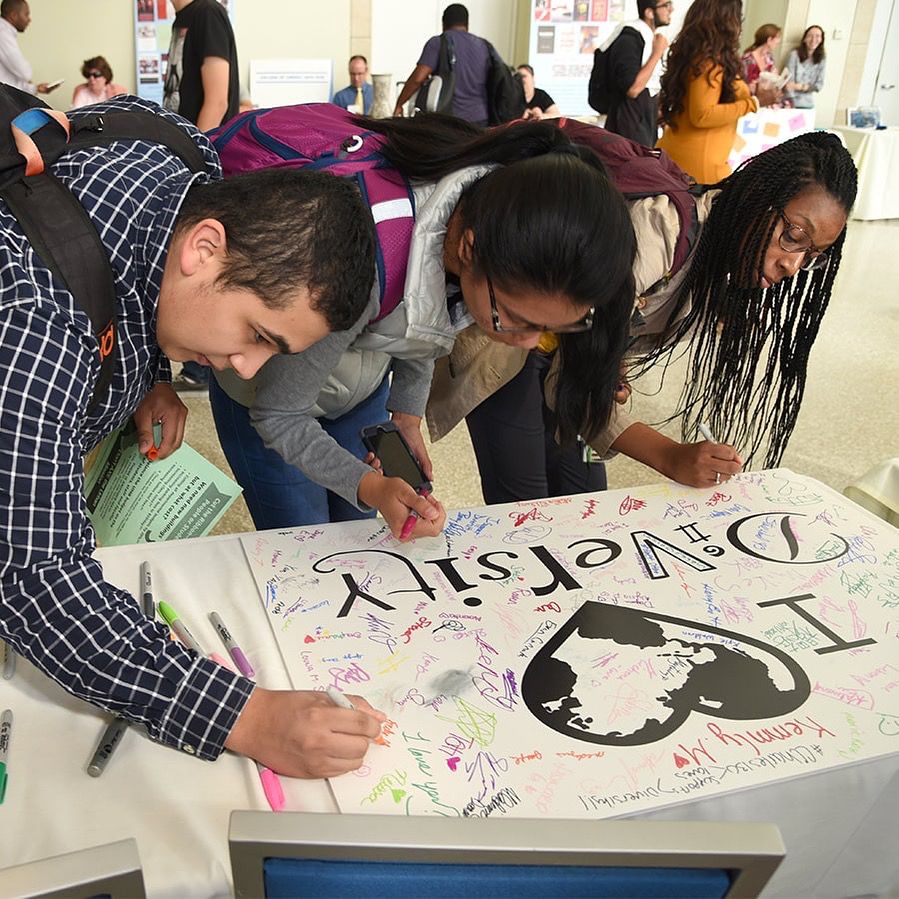 Students sign a poster that says "I heart diversity."