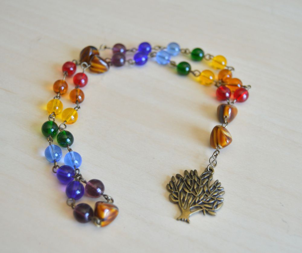 Episcopal prayer beads with rainbow weeks, woodgrain glass cruciforms, and an antiqued brass tree of life focal. 