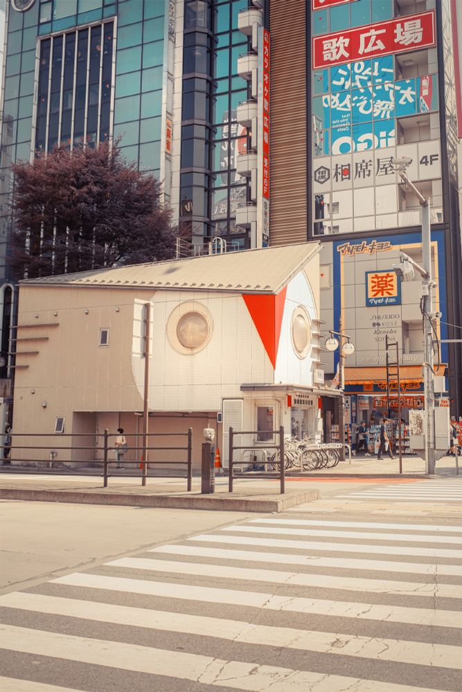 A photo of a koban (small police box) designed to look like an owl's head, with two domes as eyes and an abstract red triangle as the beak.