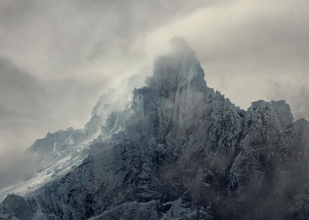 There is so much fleeting beauty to the world of mountains, lasting seconds before it's gone forever. Far above and barely visible, a towering, frozen world of snow and ice emerges every so briefly. Torres del Paine National Park, Patagonia, Chile.