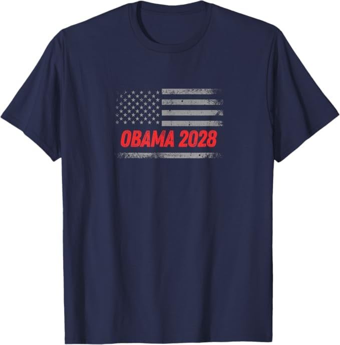 A front-facing navy blue T-shirt featuring a distressed gray-and-white American flag graphic across the chest, with the words “OBAMA 2028” in bold, worn-style red letters centered beneath the flag.
