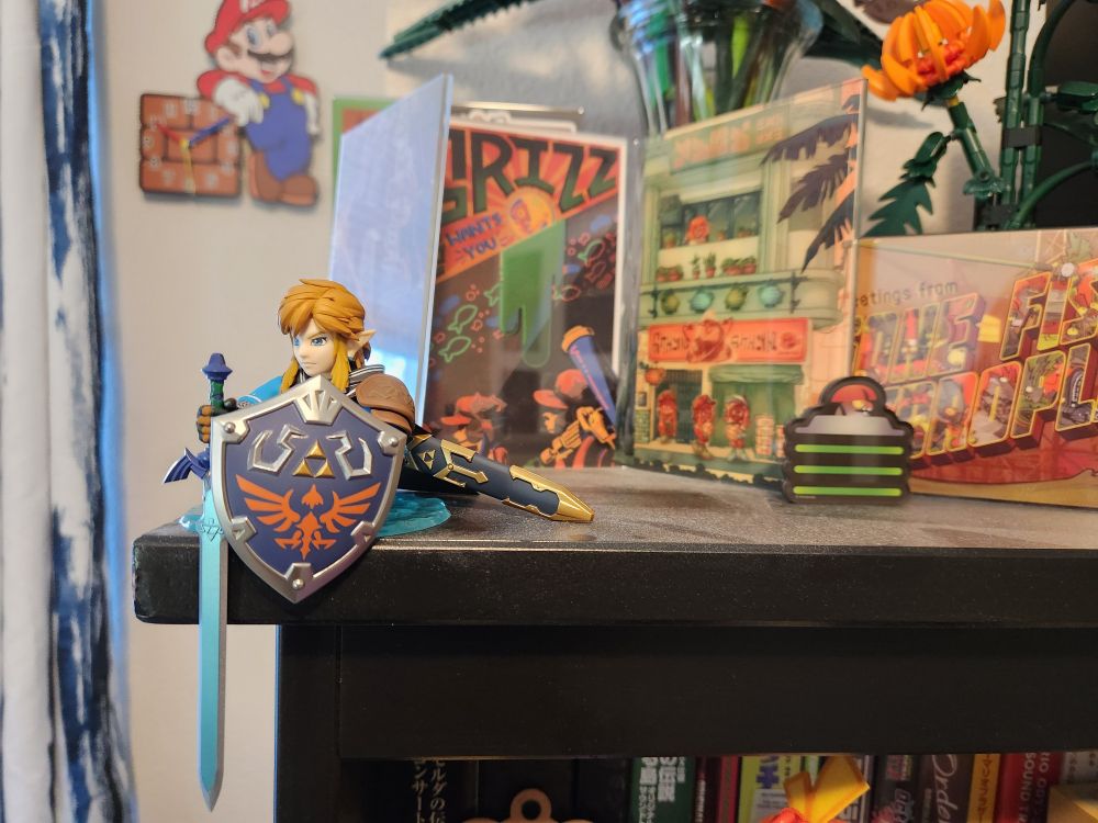 Link utilizes the Zonia ascend portal to stand as a guardian of the corner of my computer desk.  Link holds his sword and shield out as he protects my various lego flowers and Salmon Run art prints.