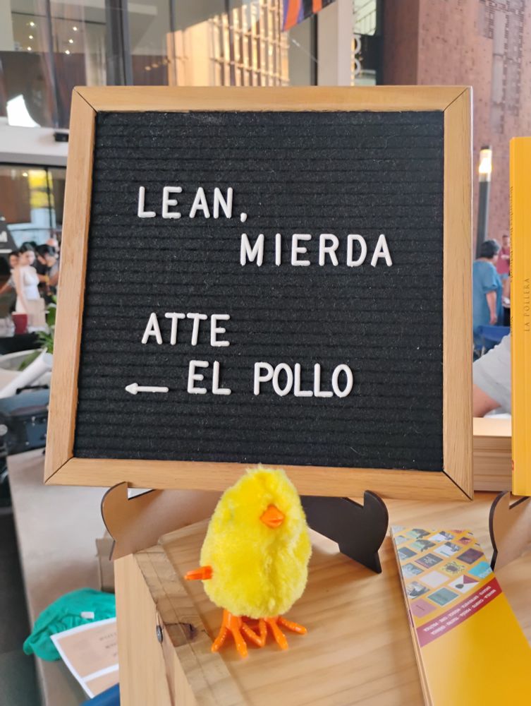 Un pollito amarillo de peluche debajo de un letrero que dice
LEAN, MIERDA 
Atte 
EL POLLO
