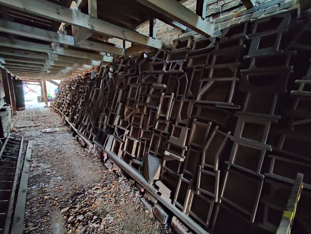 Spooky covered alleyway with one steeply sloping wall covered for the entire length in wooden brick moulds of all shapes and sizes