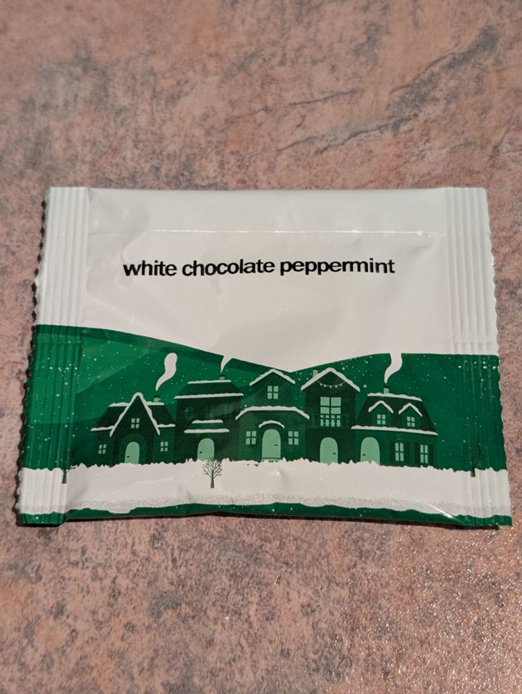 A white and green tea packet, with pictures of houses in winter.